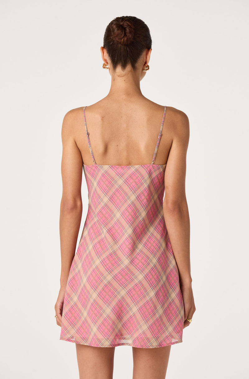 Back view of a woman wearing a pink plaid slip dress with spaghetti straps.