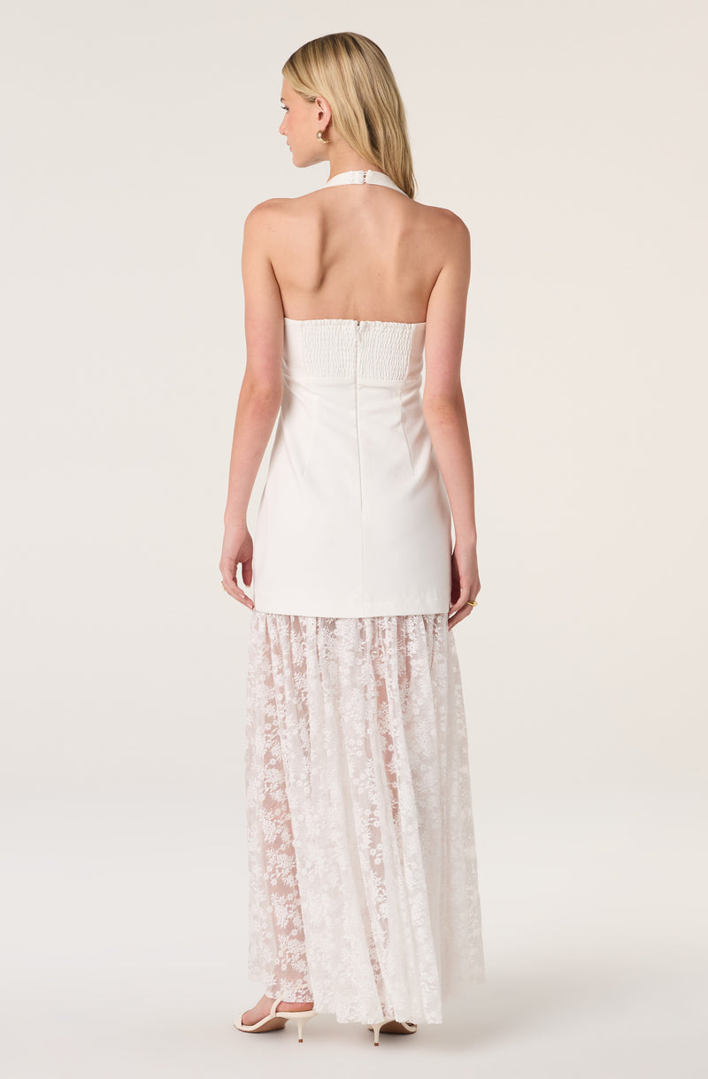 Woman in a white strapless dress with a lace skirt, facing away, with her hair down.