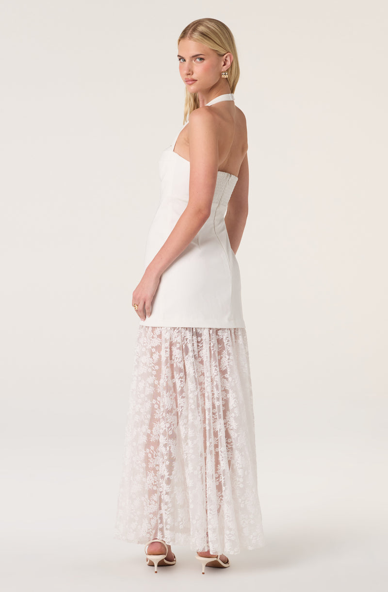 Woman in white halter dress with lace skirt and high heels, facing sideways.