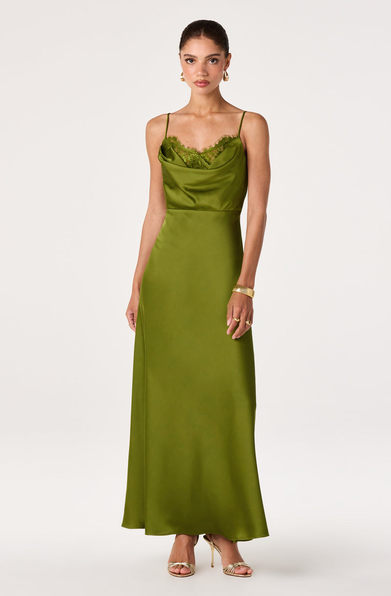 Woman in a long, satin green slip dress with thin straps and lace detail at the neckline.