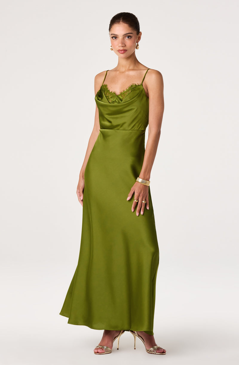 Woman in a long, shiny, green slip dress with spaghetti straps and lace trim.