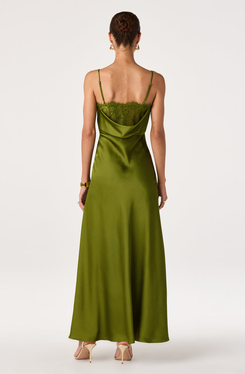 Woman in a long, green satin dress with lace detail on the back and thin straps.