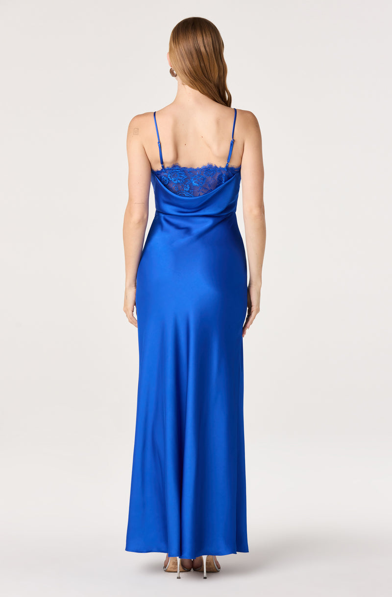 Back view of a woman in a long, shiny, royal blue satin gown with lace detail at the top and thin spaghetti straps.
