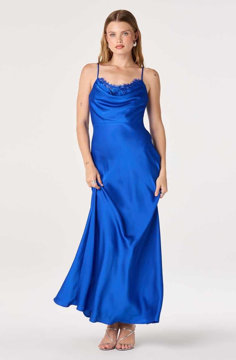 Woman in a long, blue satin slip dress with lace detail at the neckline and thin spaghetti straps.