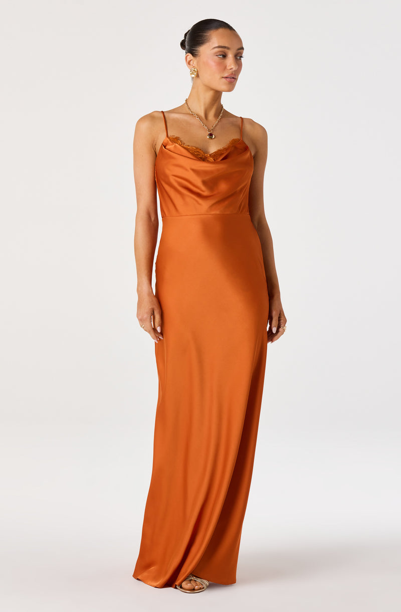 Woman wearing an orange satin slip dress with spaghetti straps and lace trim, paired with gold jewelry.