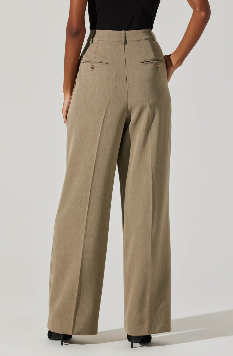 A person is wearing high-waisted, wide-leg beige trousers with a subtle plaid pattern. The trousers have front belt loops and two horizontal zippered pockets with small button accents. The person is also wearing a black top tucked into the trousers.