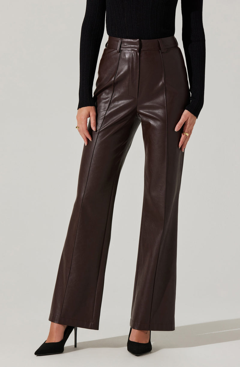 A person is wearing high-waisted, dark brown leather wide-leg pants paired with a black ribbed long-sleeve sweater and black pointed-toe high heels.