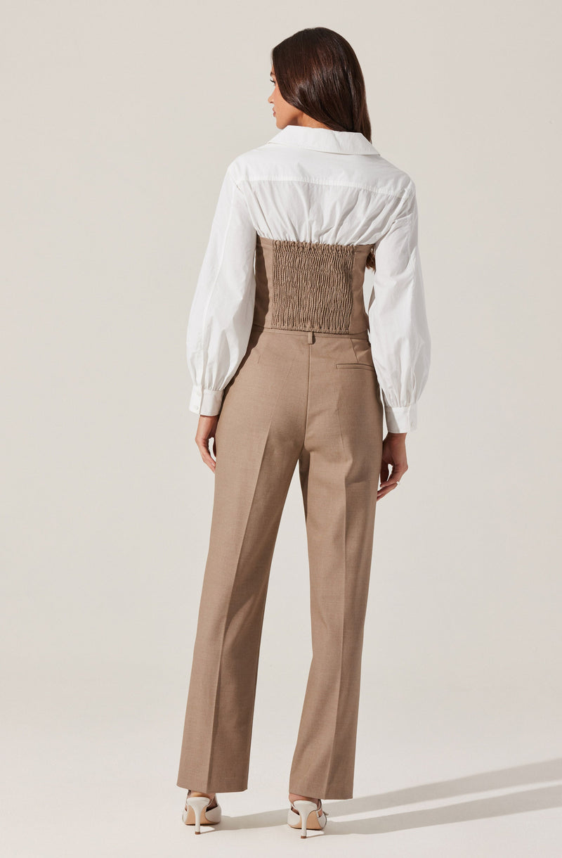 A woman is wearing a white long-sleeved shirt with a collar and puffed sleeves, paired with fitted high-waisted beige trousers that have a classic, tailored fit. The trousers have a straight leg cut and a front crease, and she is wearing white high-heeled shoes.