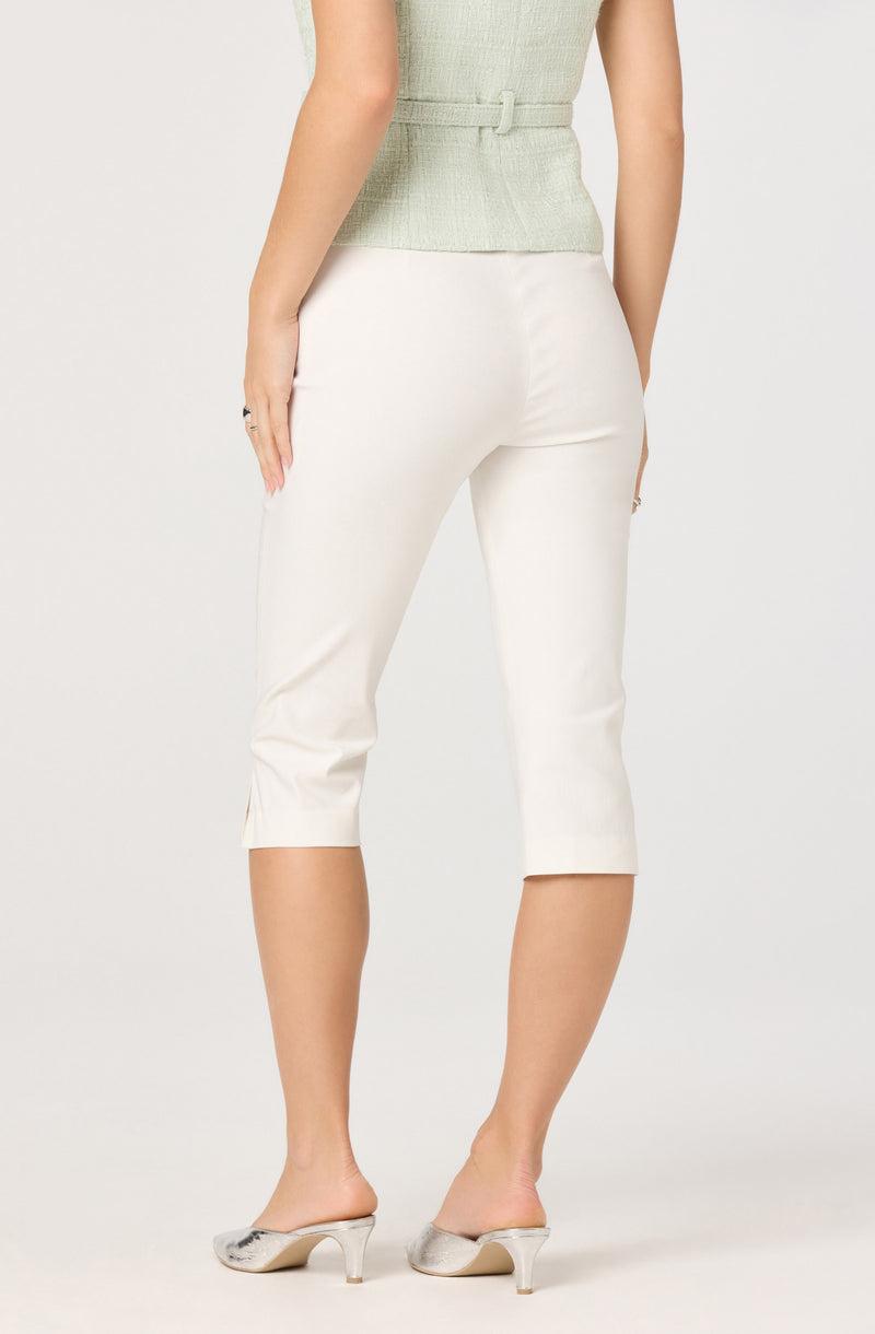 Light green sleeveless top and white cropped pants with side slits, paired with silver heels.