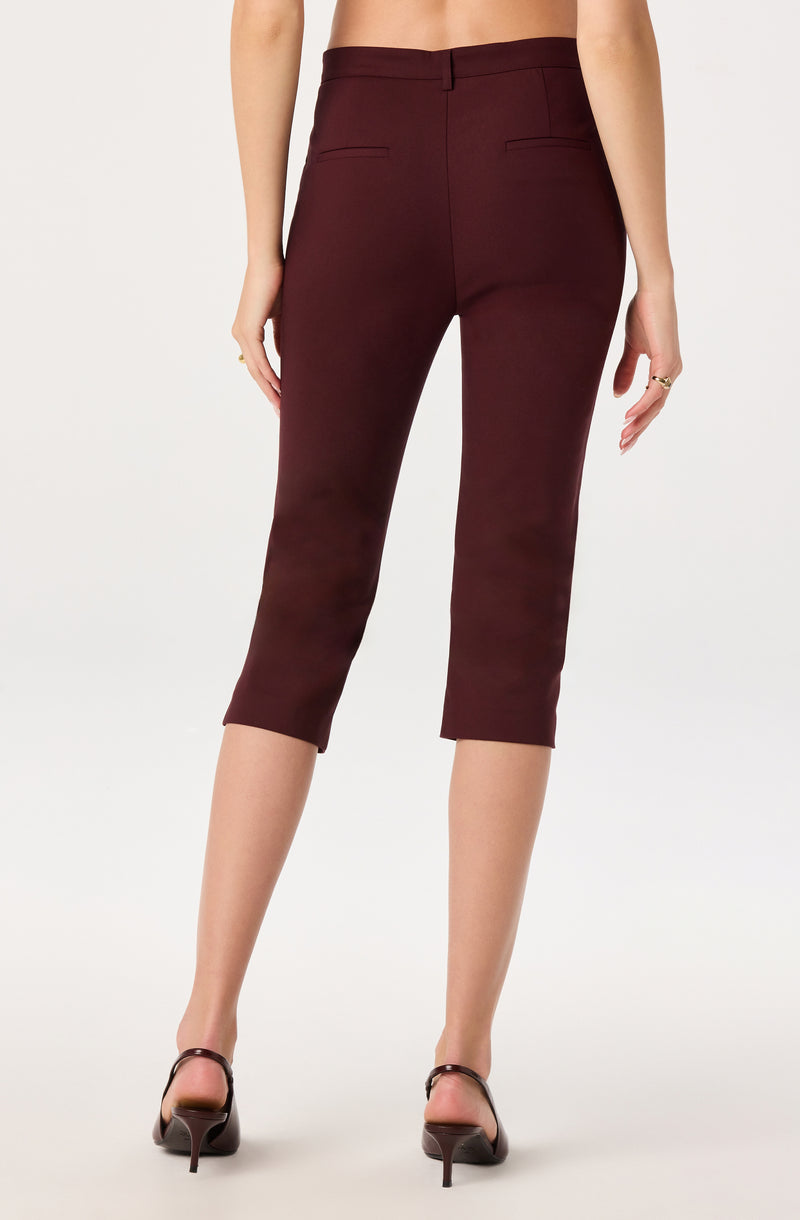 Woman wearing maroon ankle-length trousers and black heels.
