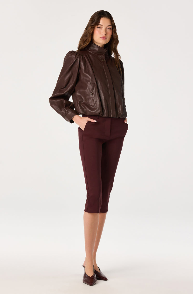 Woman wearing a dark brown leather jacket and burgundy capri pants.