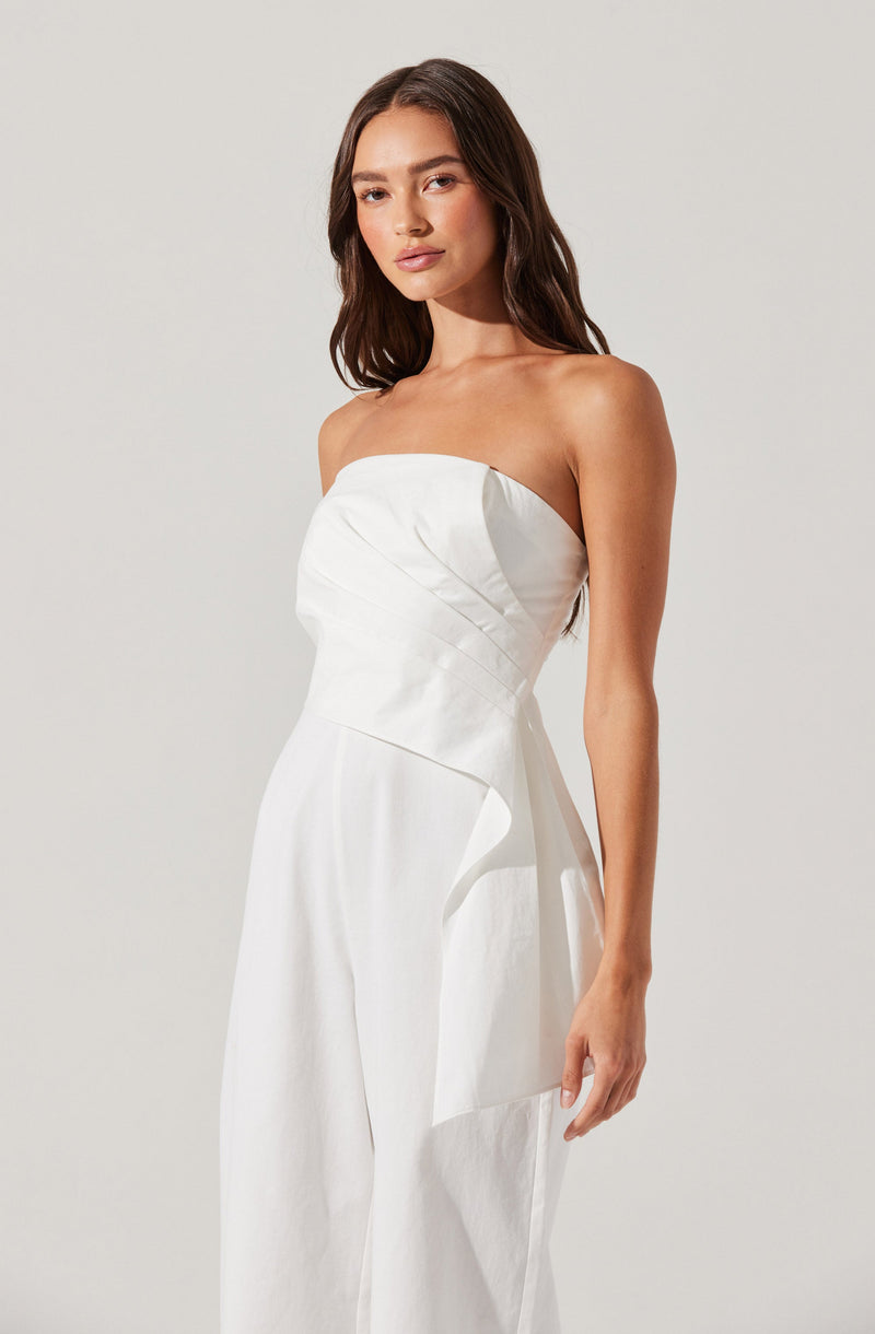A woman wearing a strapless white dress with a fitted bodice that has diagonal seam details. The skirt of the dress is full-length and appears to be wide-legged. The fabric looks smooth and slightly shiny, giving an elegant appearance.
