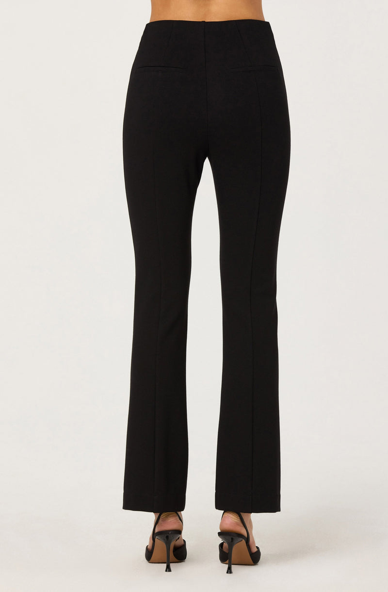 A person is wearing high-waisted black pants with a straight-leg fit that extend to the floor, paired with black high-heeled sandals. The pants have a smooth waistband without visible belt loops and appear to have a tailored fit.