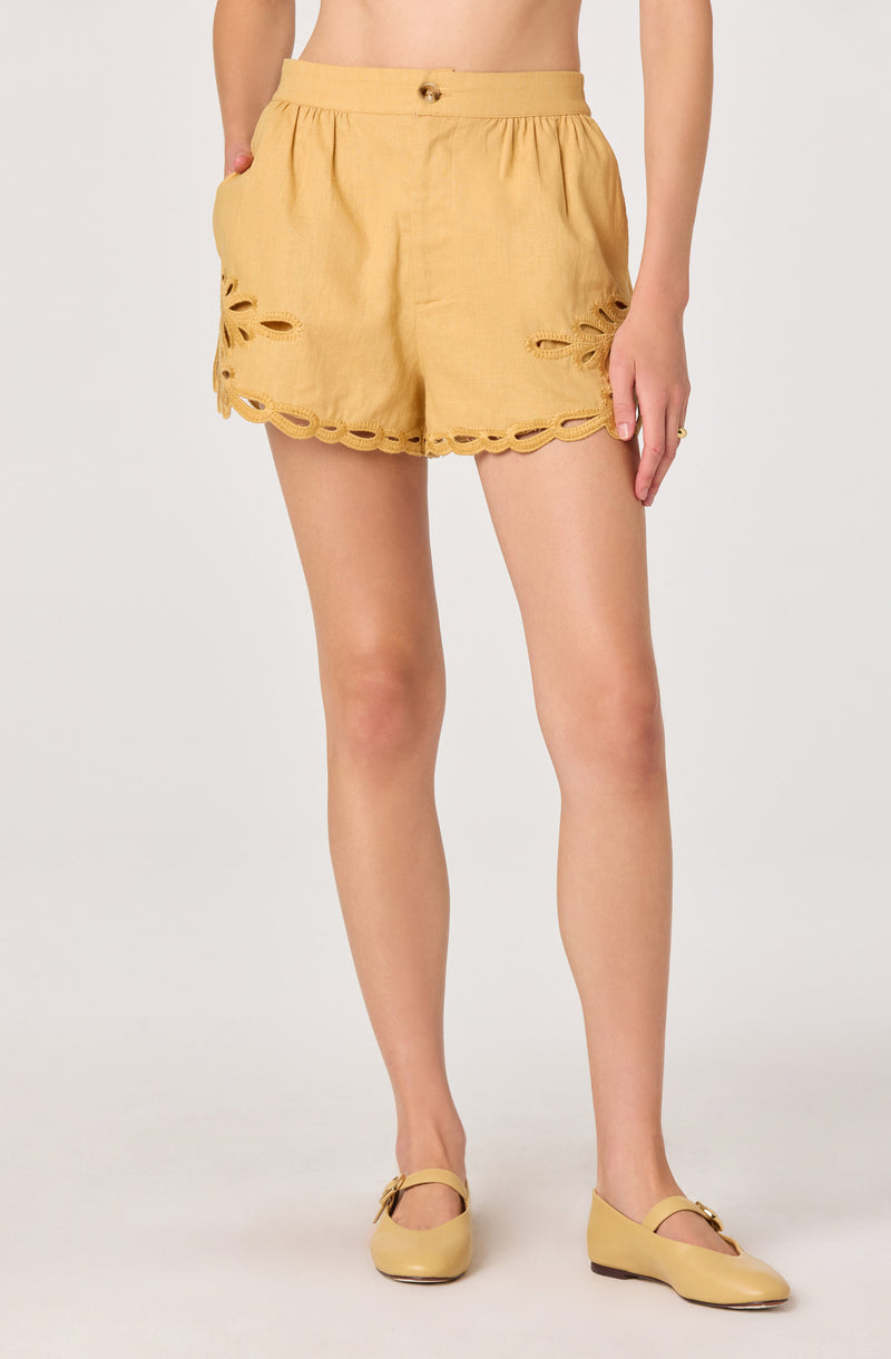 Yellow shorts with scalloped hem and cutout floral details, paired with matching yellow shoes.