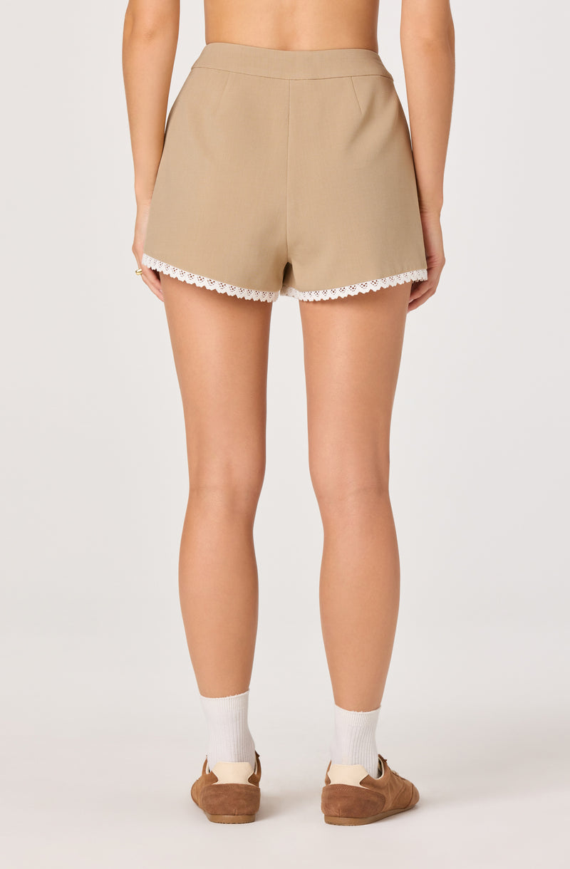 Beige shorts with white lace trim at the hem, worn with white socks and tan shoes.