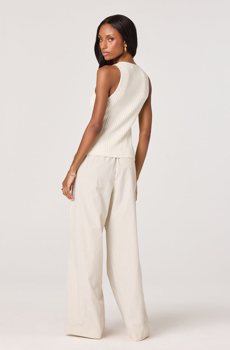 Woman in cream sleeveless ribbed top and wide-leg striped pants, facing slightly away.