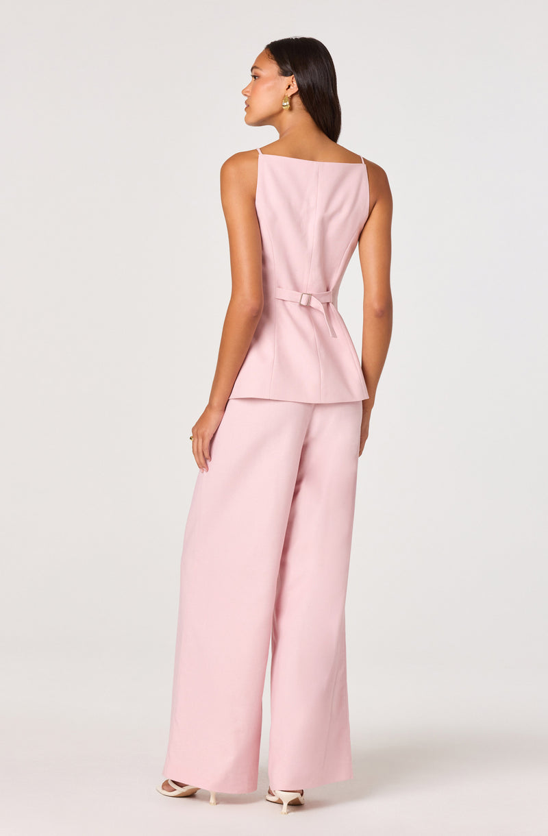 Woman in pink sleeveless top with a waist belt and wide-leg pants.