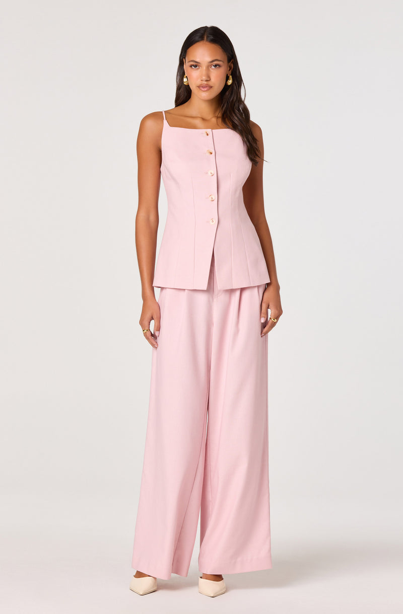 Woman in a light pink sleeveless top with buttons and wide-leg pants.