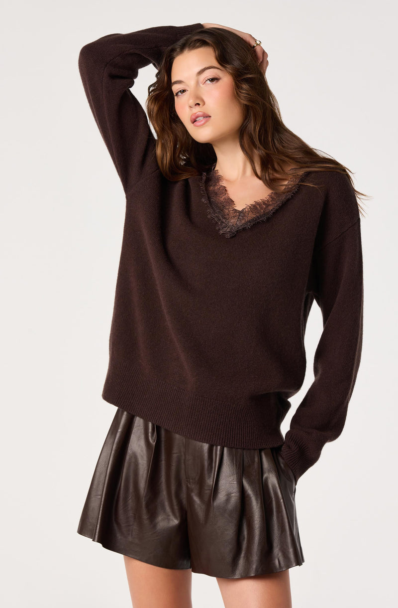 Woman wearing a dark brown sweater with lace neckline and leather shorts.