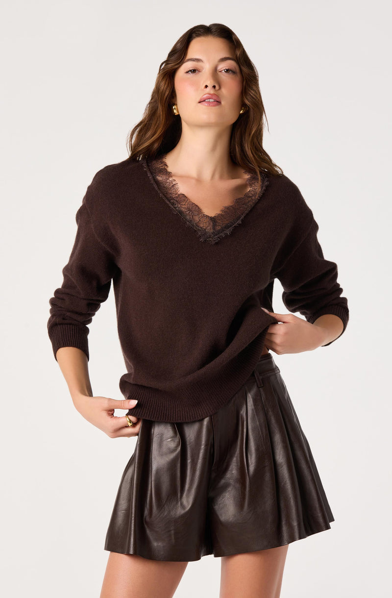 Woman wearing a dark brown sweater with lace trim and matching leather shorts.