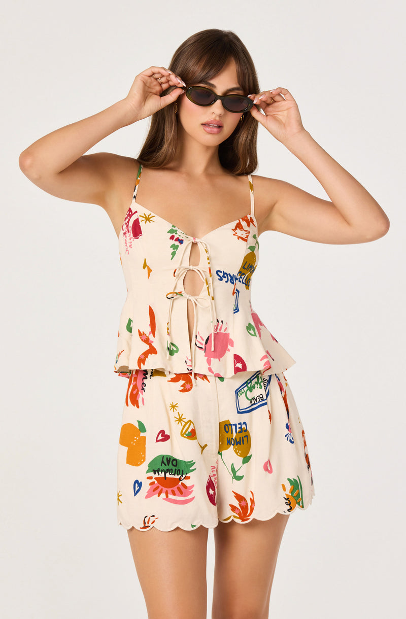 Woman in colorful printed tank top and shorts, wearing sunglasses.