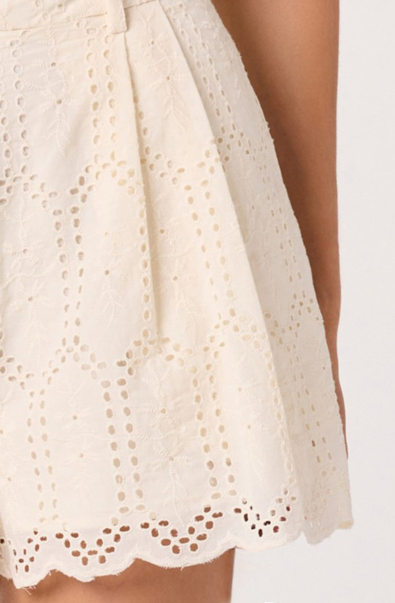 Cream-colored dress with eyelet embroidery and scalloped hem.