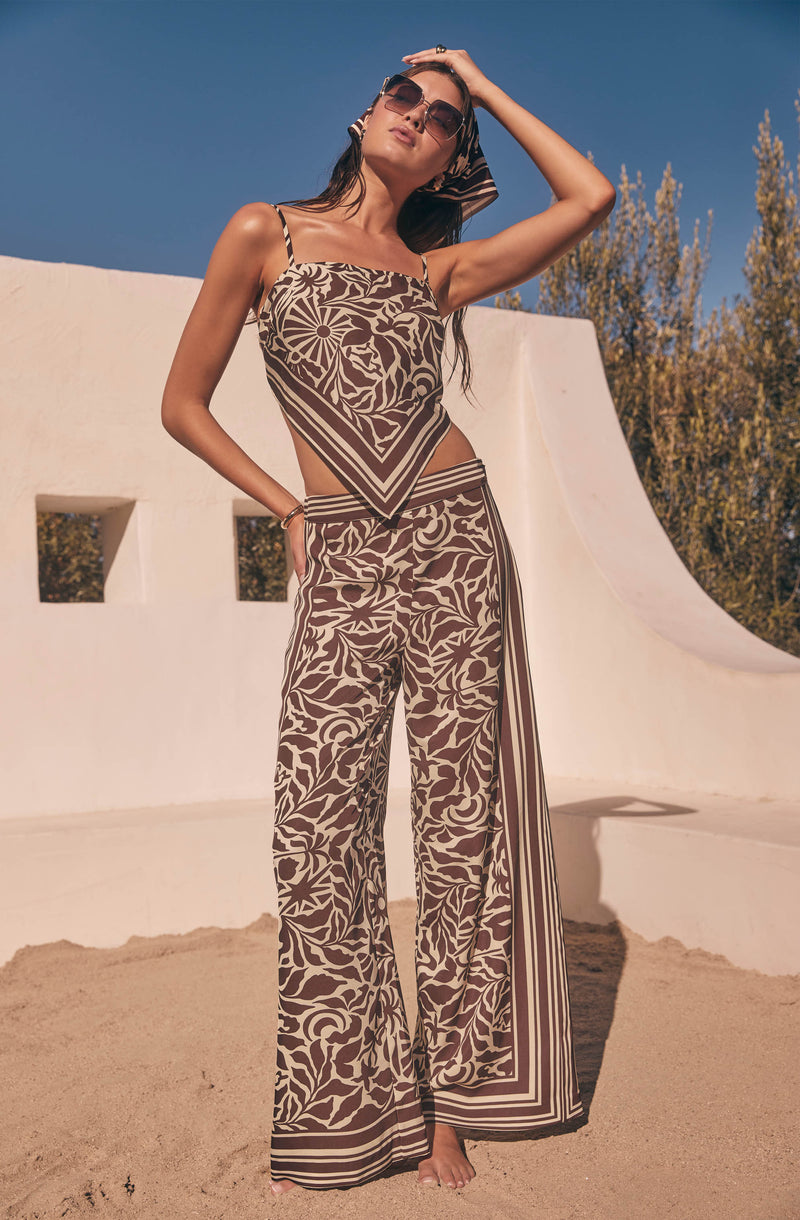 Woman in matching brown and beige floral crop top and wide-leg pants with geometric border patterns.