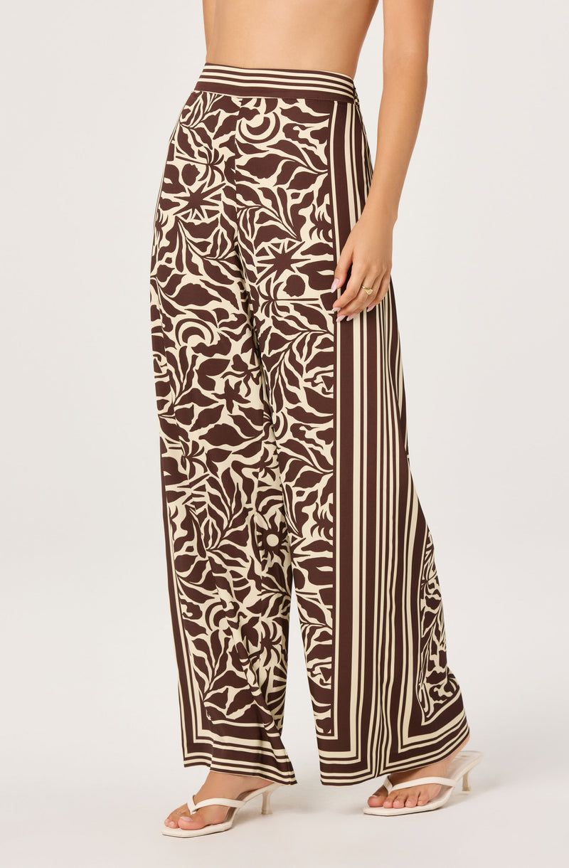 Wide-leg pants with a brown and cream floral and geometric pattern, high waist, and stripe detailing.