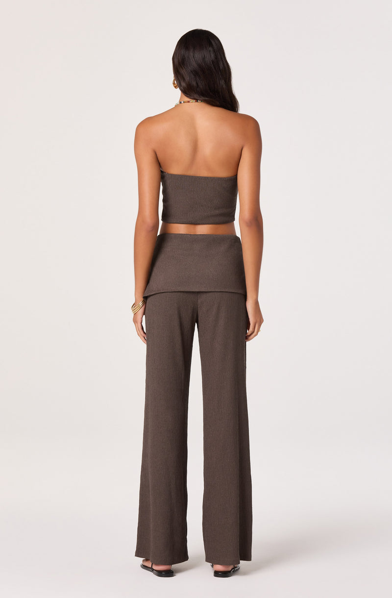 Woman wearing a strapless brown top and matching high-waist wide-leg pants.