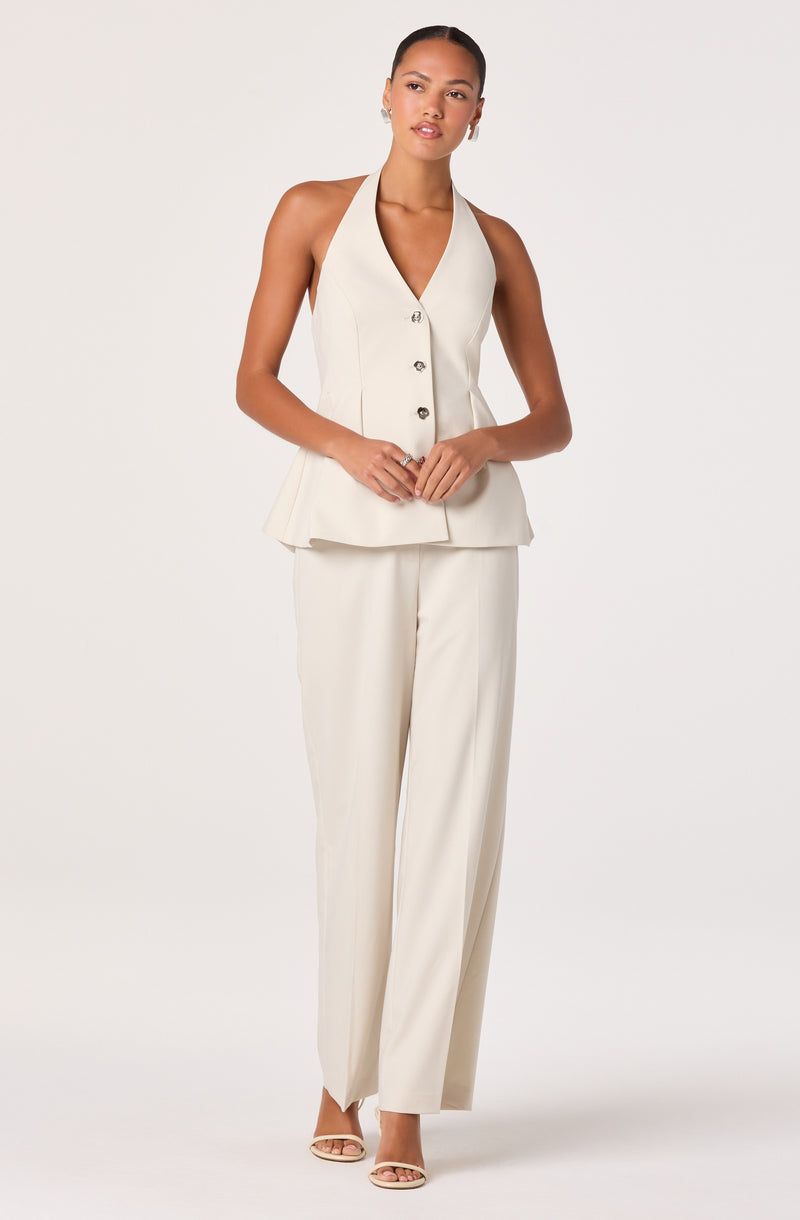 Woman in a sleeveless, cream-colored, button-up top with wide-leg pants.