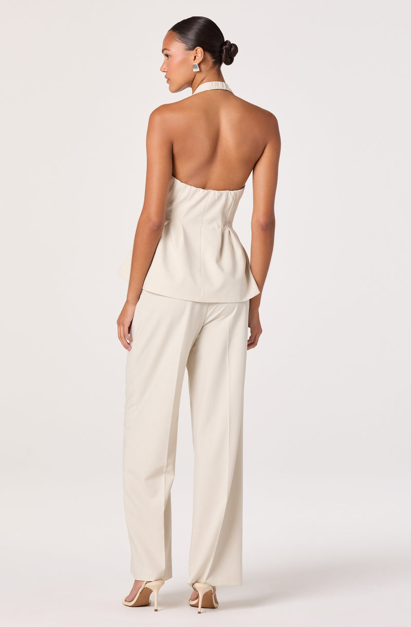 Woman in a sleeveless beige top and matching wide-leg pants, with a halter neckline and open back.