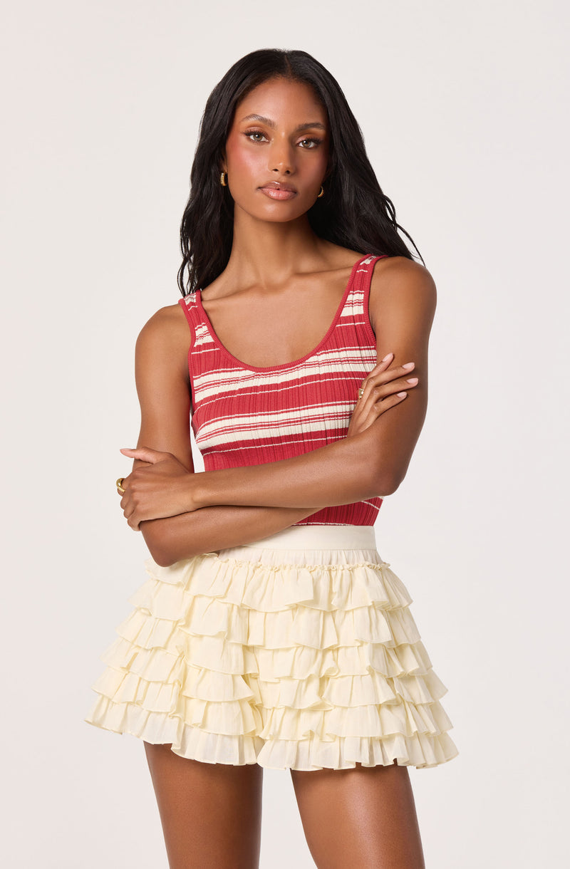 Woman in red striped tank top and cream ruffled skirt with layered tiers.