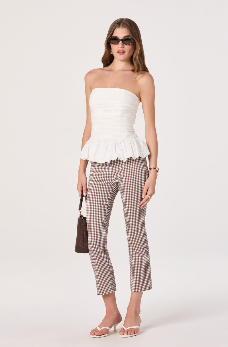 Strapless white top with ruffle hem and checkered pants with brown and white pattern.