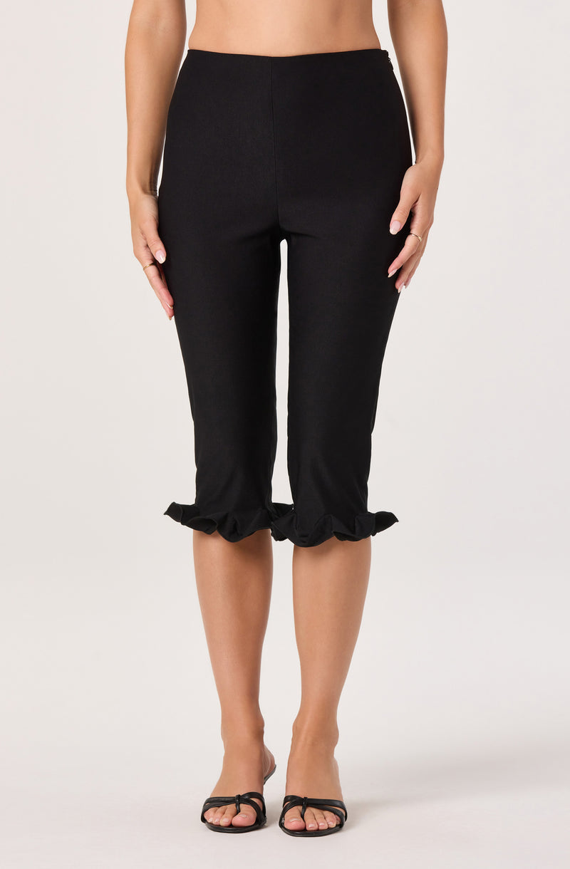 Black cropped pants with ruffled hems at the cuffs, worn with black open-toe heels.