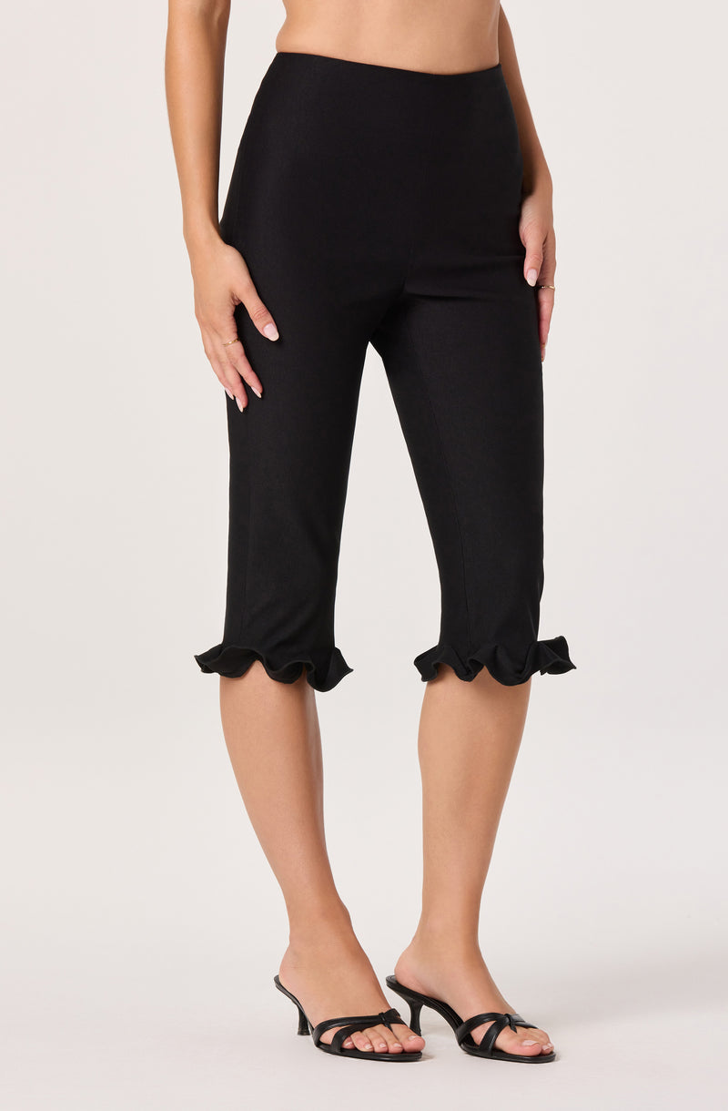 Black cropped pants with ruffled hems, paired with black heeled sandals.