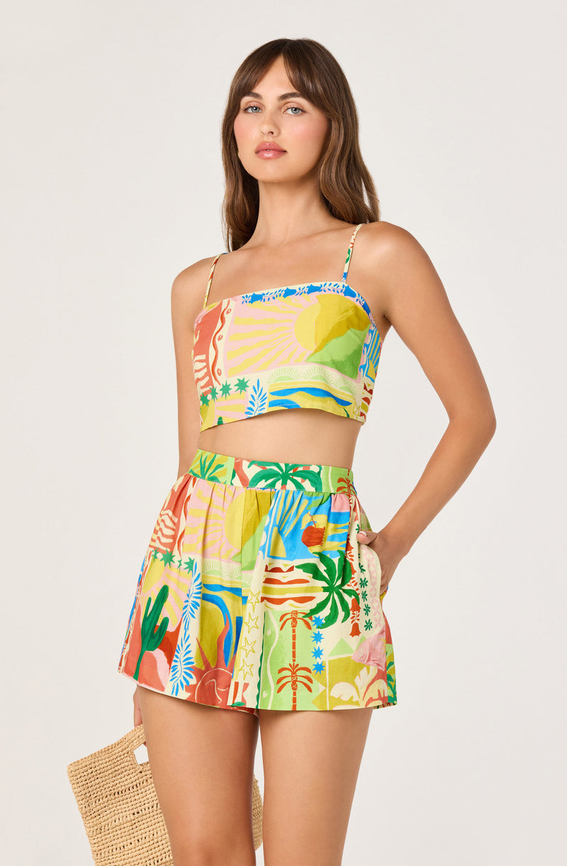 Woman wearing a colorful tropical print matching crop top and shorts set with spaghetti straps.