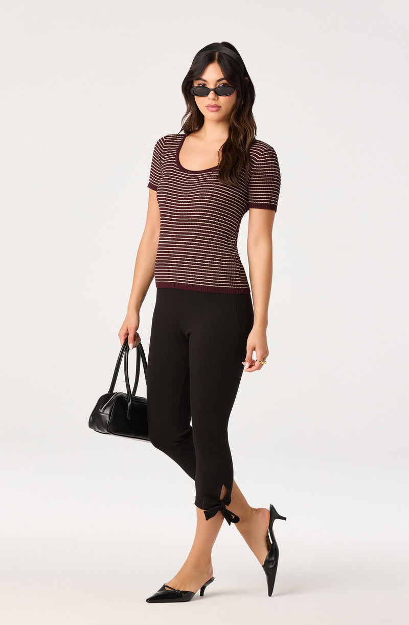 Striped short-sleeve top and black cropped pants with tied ankles, styled with black heels and sunglasses.