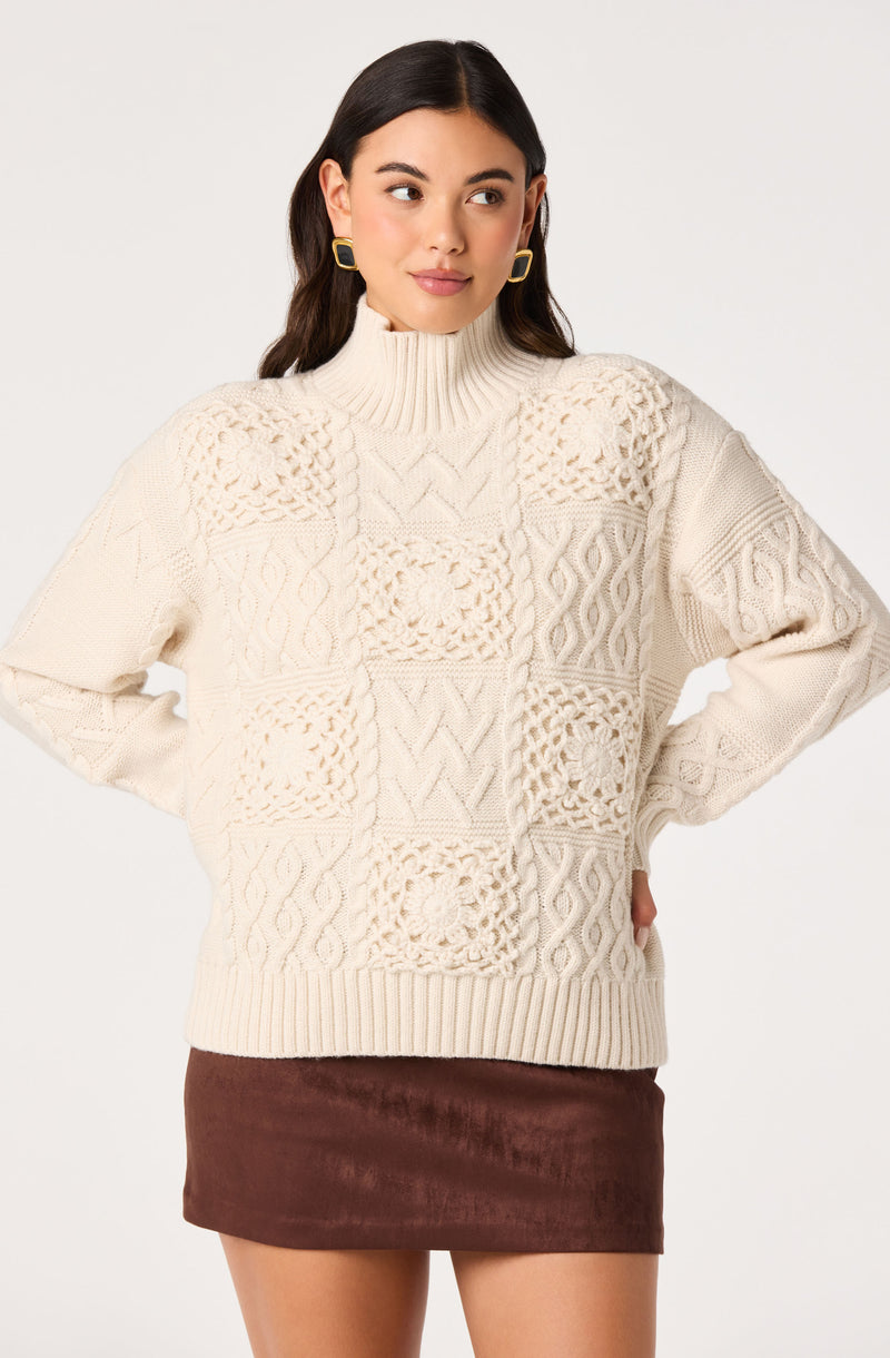 Young woman in a cream knitted sweater with textured patterns and a brown suede mini skirt.