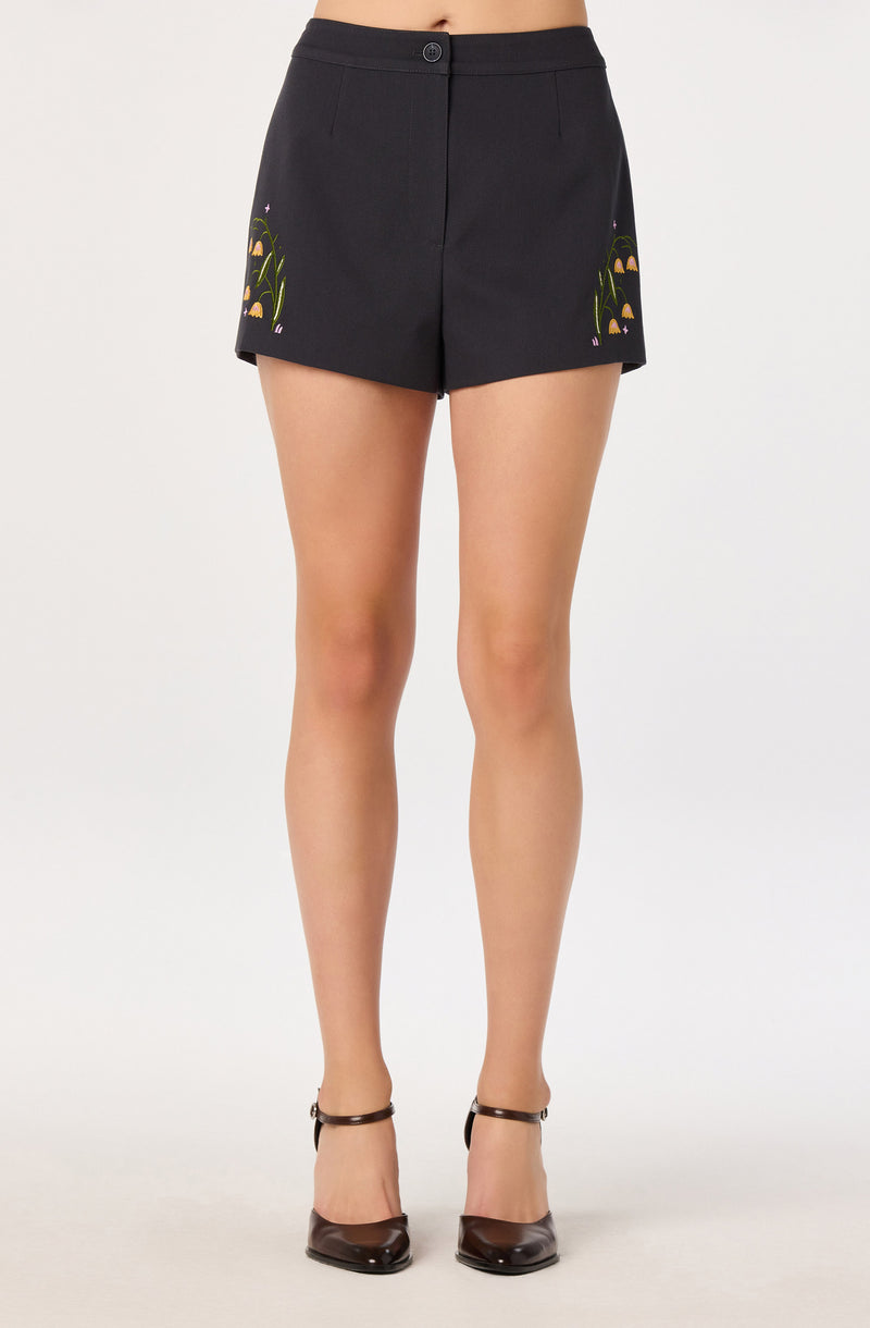 Black shorts with embroidered floral designs on sides, high-waisted, with a button at waist.