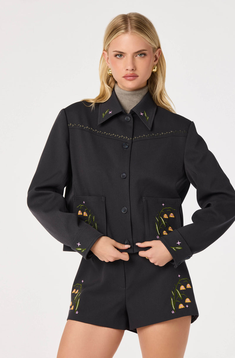 Black jacket and shorts set with floral embroidery, collar with embroidered stars, and gold accessories.