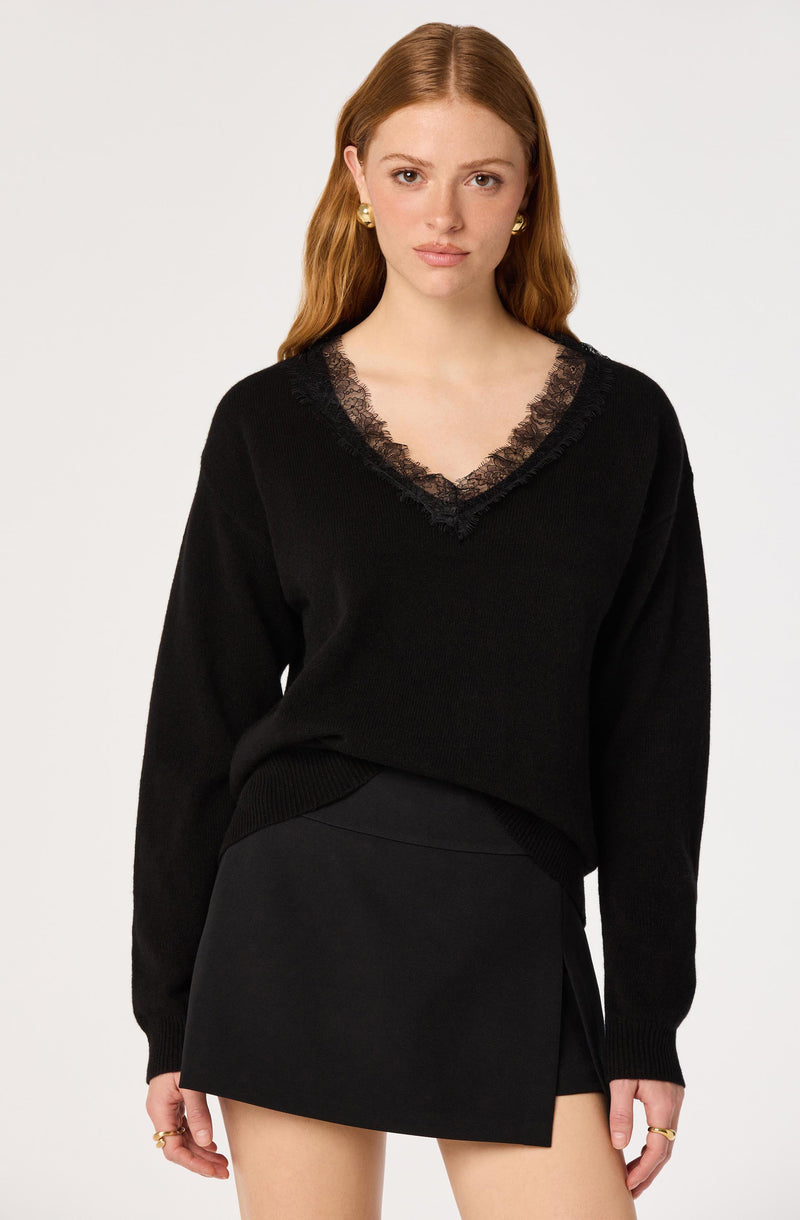 Black sweater with lace-trimmed V-neck, paired with a black asymmetrical skirt.