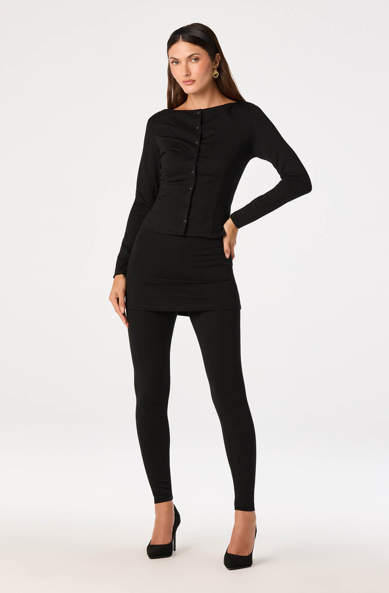 Woman wearing a black long-sleeve top and a fitted black skirt with black high heels.