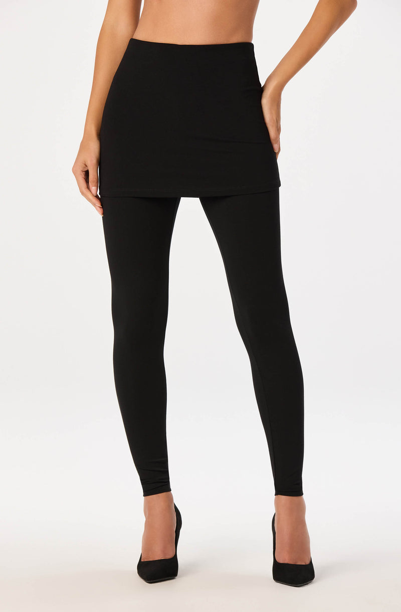 Woman wearing a black high-waisted skirt, black leggings, and black heels.