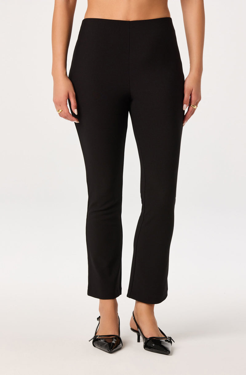 Women wearing black tailored pants with a high waist and straight legs, paired with black high heels.
