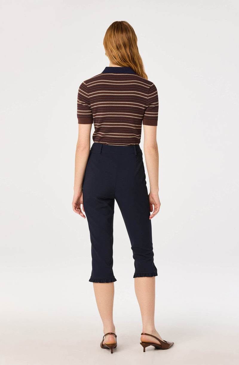 Woman wearing a striped short-sleeve polo shirt and navy cropped pants with ruffled hems.