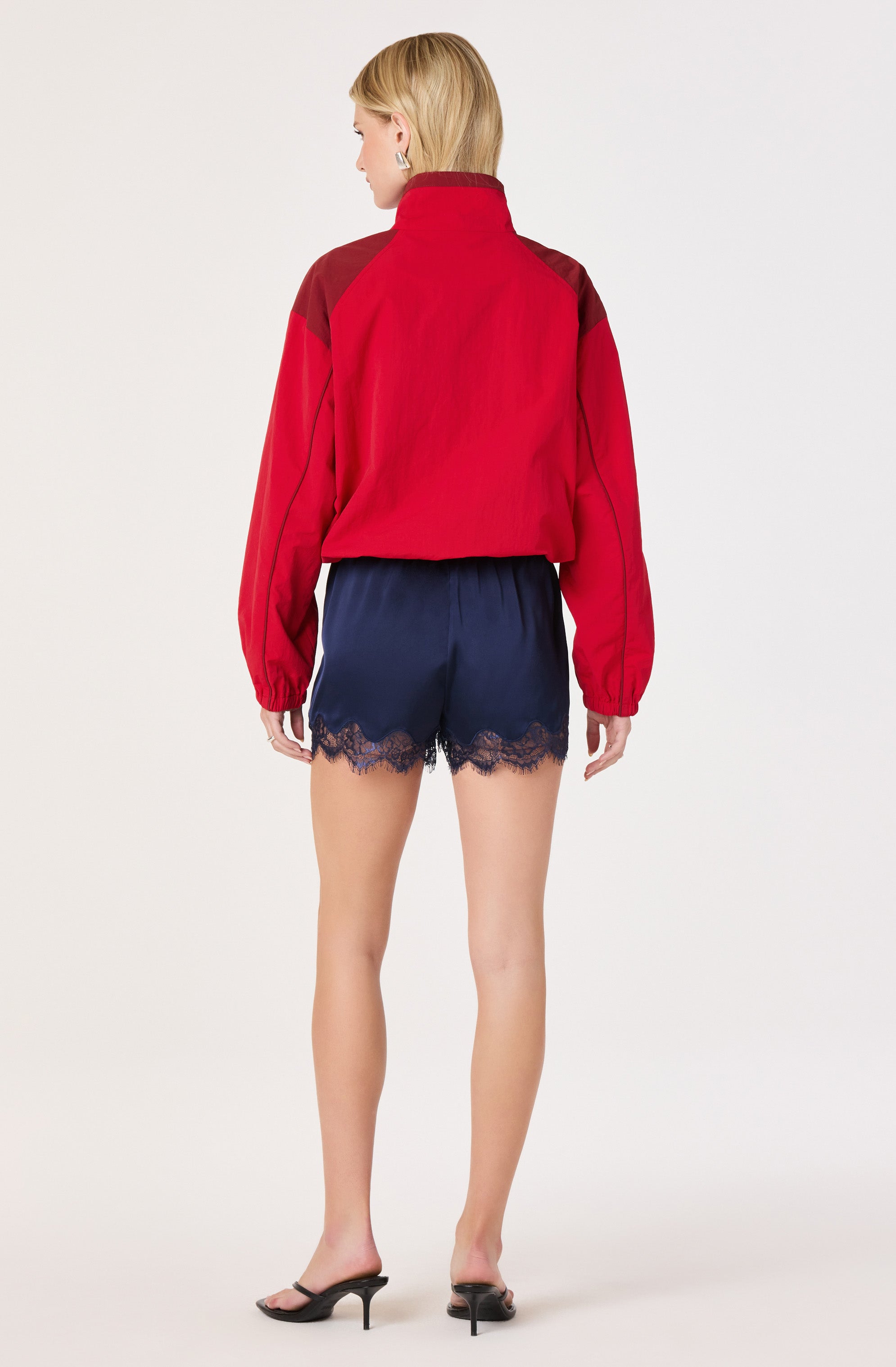 Woman wearing a red and brown jacket with navy blue shorts featuring lace trim.