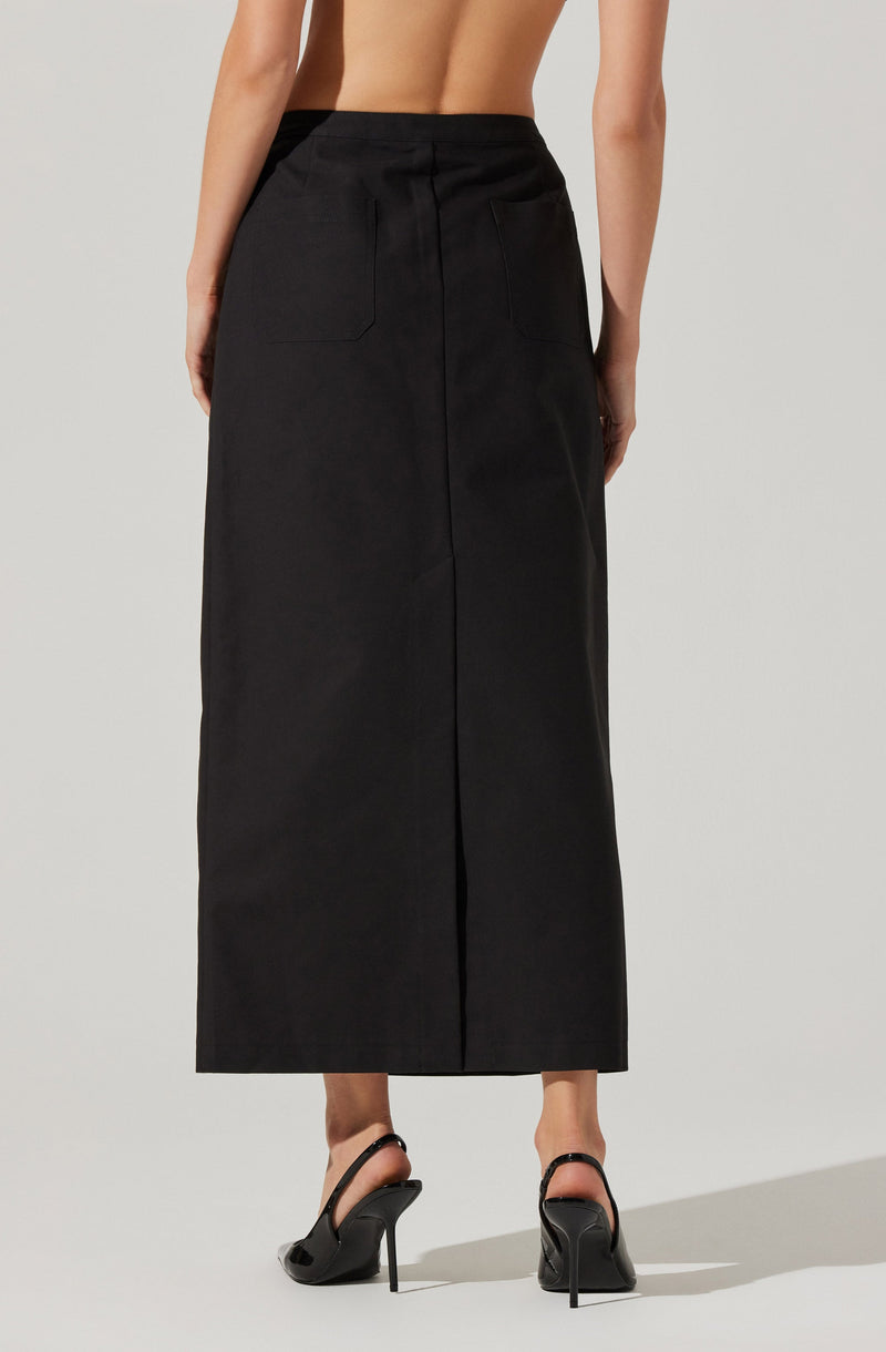 A person is wearing a long, black, high-waisted skirt that reaches the ankles. The skirt has a fitted waistband and features two back pockets. The individual is also wearing black high-heeled shoes with ankle straps.