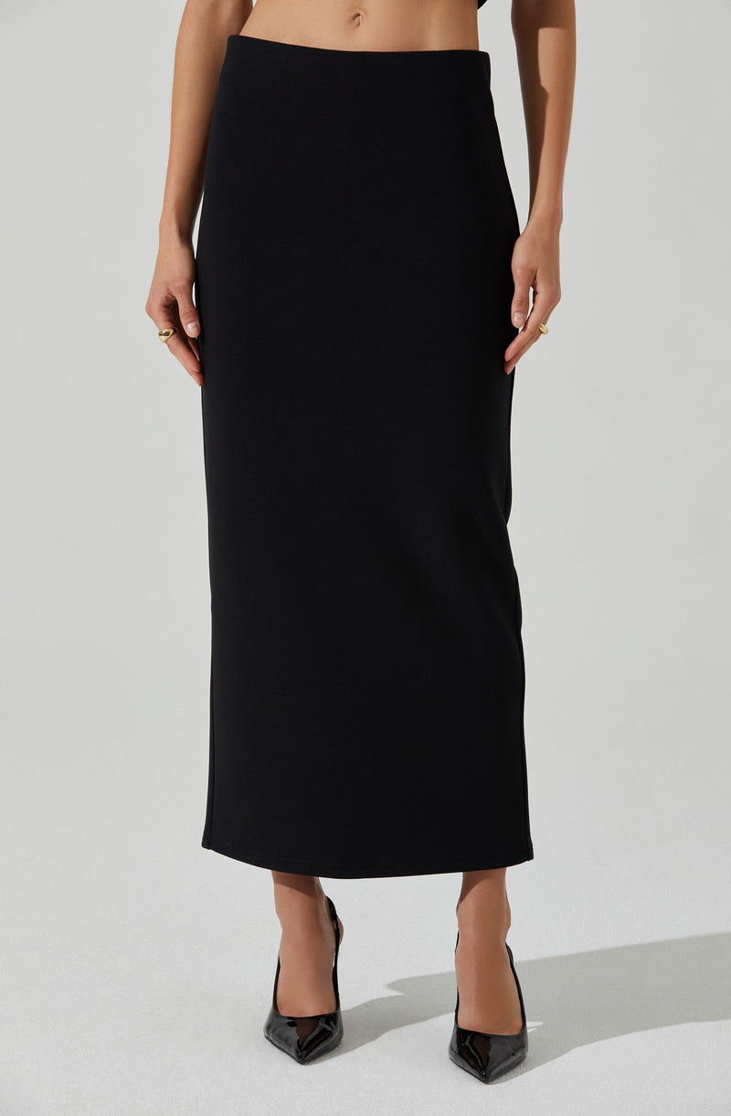 A woman is wearing a long, black, fitted skirt that reaches down to her ankles. She is also wearing black high-heeled shoes. The focus is on the simplicity and elegance of the black clothing.