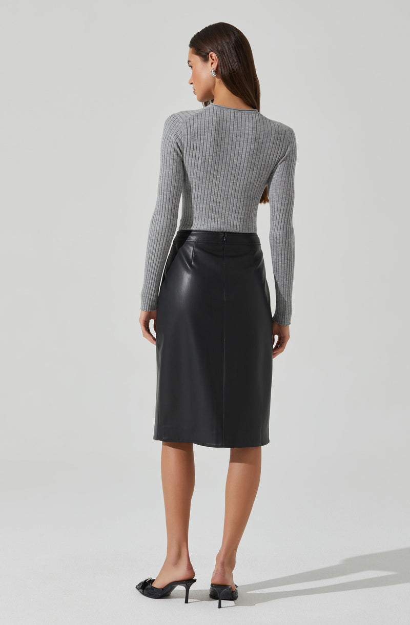 A woman is wearing a fitted, long-sleeve, gray ribbed knit sweater with a crew neckline. She pairs it with a high-waisted, black leather midi skirt that falls below her knees. She completes the outfit with black open-toe heels.