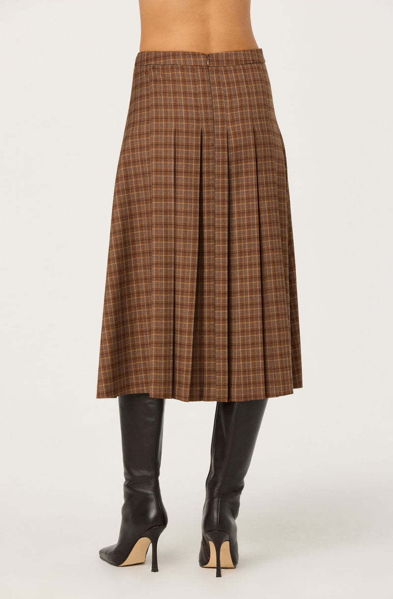 Brown plaid midi skirt with pleats, paired with tall black high-heeled boots.